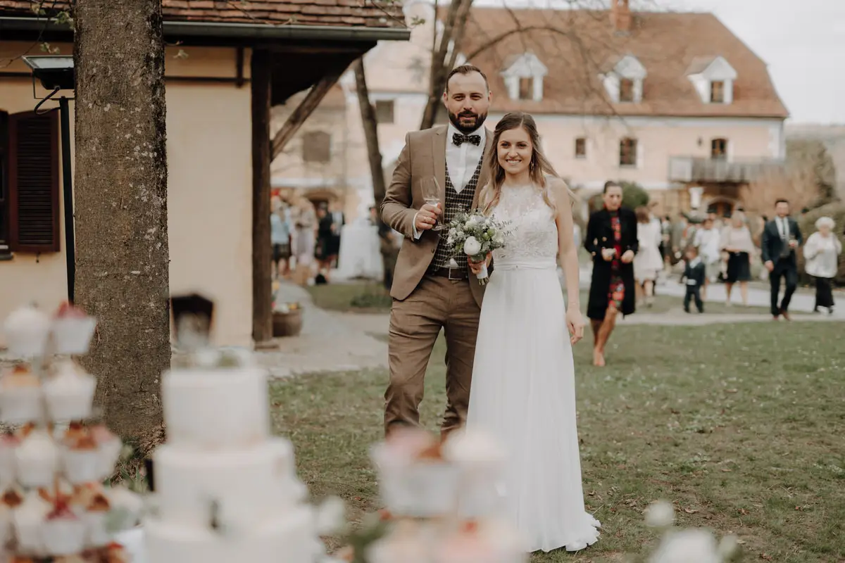 Brautpaar betrachtet gemeinsam die Hochzeitstorte unter freiem Himmel