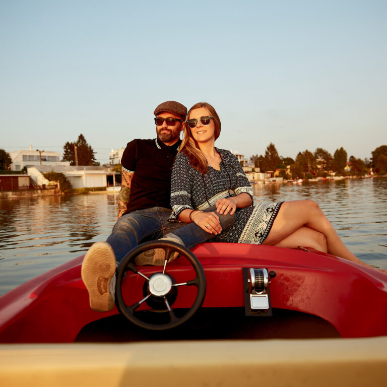 Paarfoto von Michi und Marc am Kaiserwasser in Wien, beide sitzen gemeinsam auf einem Elektroboot, Feature Image