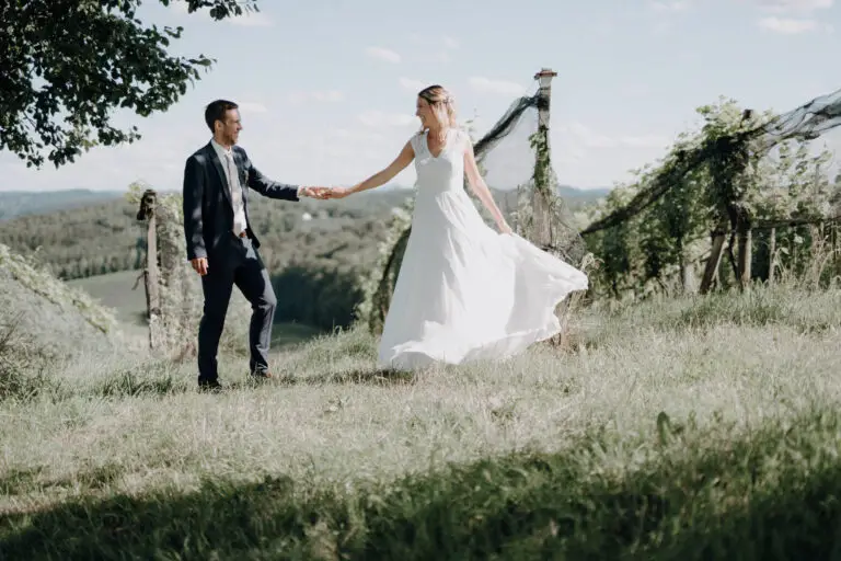 Katja dreht sich im Weinberg zu Philip, beide halten Händchen – Hochzeitsfotos in der Oststeiermark