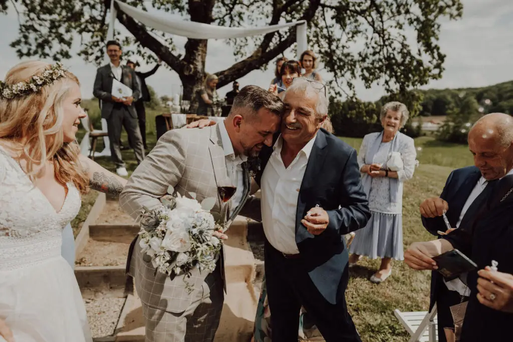 Der Vater des Bräutigams gratuliert seinem Sohn während des Auszugs nach der Trauung